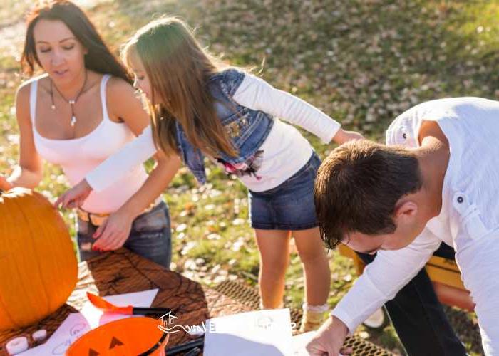 50+ Ιδέες για Φθινοπωρινές Δραστηριότητες που Κάθε Οικογένεια Πρέπει να Δοκιμάσει 5 Οικογένεια να σκαλίζει κολοκύθες έξω σε τραπέζι