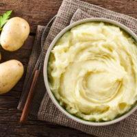 Τέλειος Instant Pot Πουρές Πατάτας (+ Συμβουλές Κατάψυξης & Αναθέρμανσης) 7 Πουρές πατάτας Instant Pot σε μπολ με ωμές πατάτες δίπλα σε τραπέζι