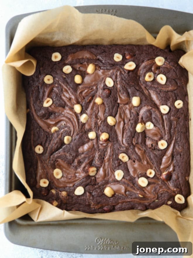 Stack of fudgy Nutella brownies with hazelnuts on a wire rack, cooling