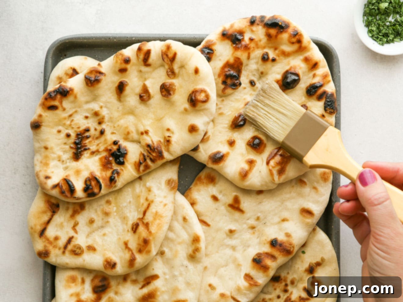 brushing grilled flatbread with butter