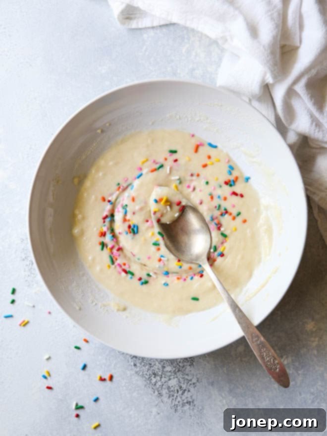 Small batch funfetti cake batter, generously speckled with colorful rainbow sprinkles, ready to be poured into cupcake liners.