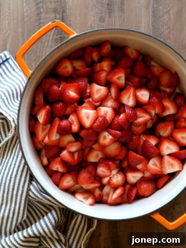 Close-up of freshly made strawberry jam simmering in a pot, showing its rich color and texture.