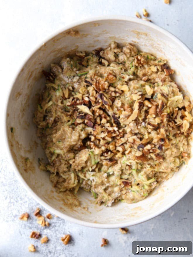 Mixing the wet and dry ingredients for homemade banana zucchini walnut bread batter.