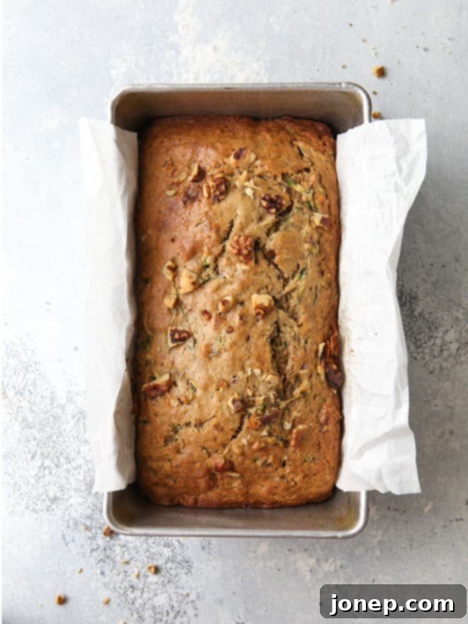 Two perfectly baked loaves of banana zucchini walnut bread cooling on a wire rack.