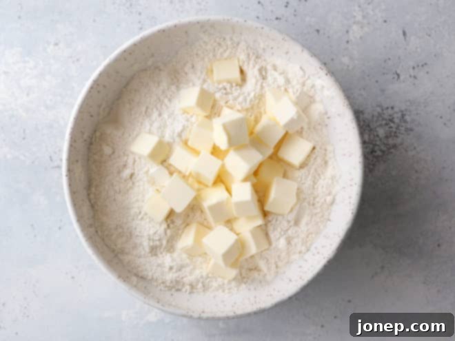 Cold butter cubes tossed with flour in a mixing bowl for pie crust.