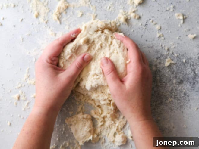 Shaping pie crust dough into two flat disks on a work surface.