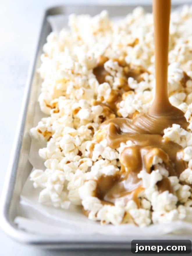 Pouring rich, gooey caramel sauce over a mountain of freshly popped popcorn for an irresistible treat.