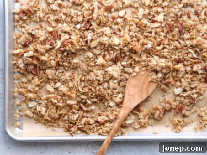 Freshly baked homemade granola broken into large, tempting clusters on a baking sheet.