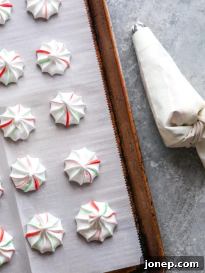 piped meringues on a sheet pan with piping bag