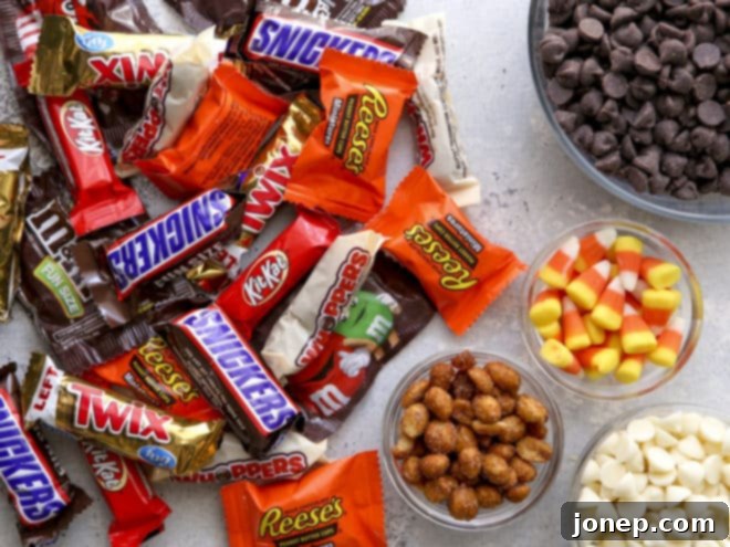Halloween Candy Bark 3 A collection of ingredients for Halloween candy bark, including chocolate, various candies, and peanuts