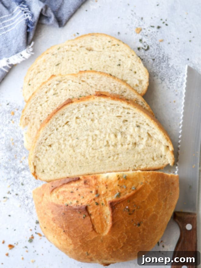 A slice of golden-brown Dutch oven herb bread revealing its soft, airy interior.