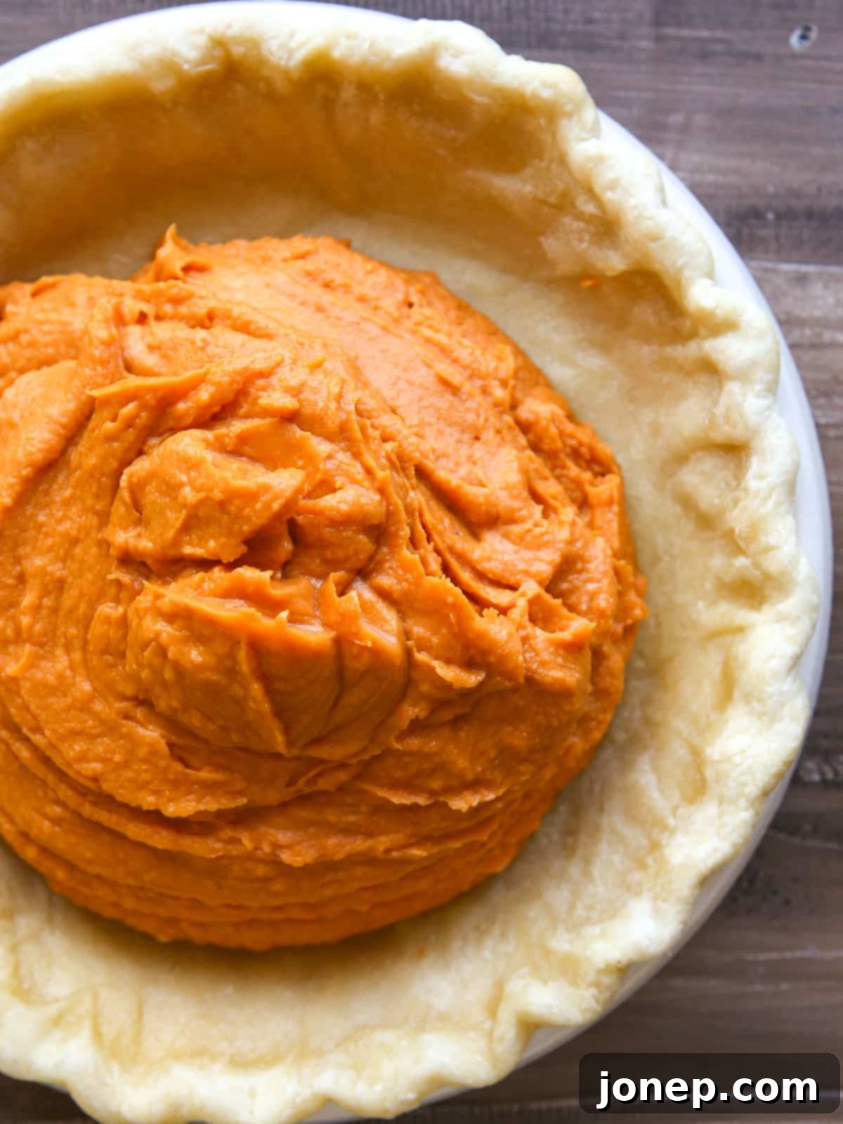 poured sweet potato filling inside par baked pie crust, ready for baking