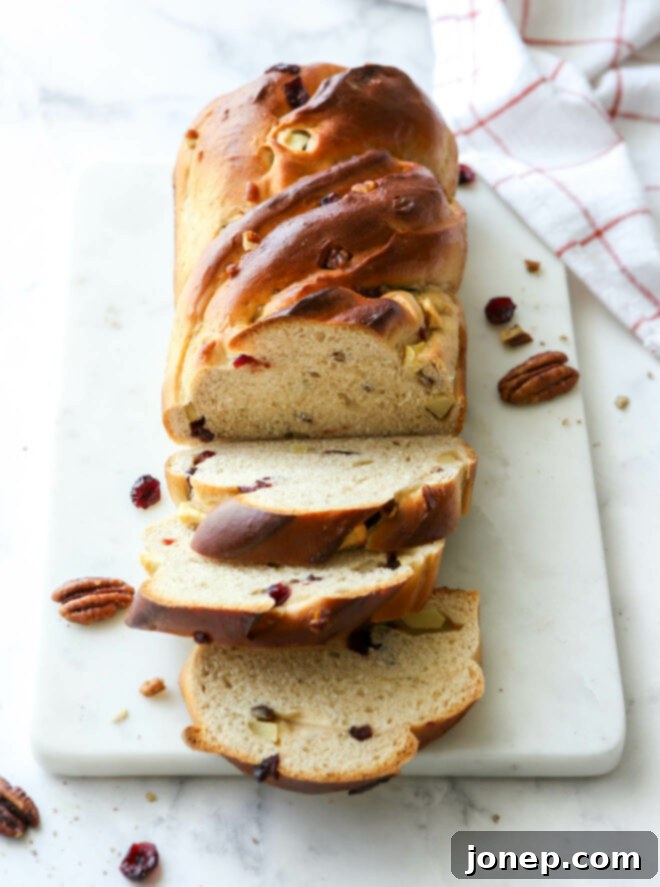 Warm Apple Cranberry Bread 2 An inviting angle view of a freshly baked apple cranberry bread, sliced and presented beautifully on a platter, showcasing its soft interior, juicy cranberries, and chopped apples.