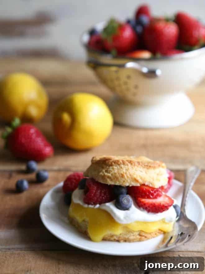 Overhead view of a beautifully plated Lemon Berry Shortcake with a spoonful of lemon curd, ready for a bite.