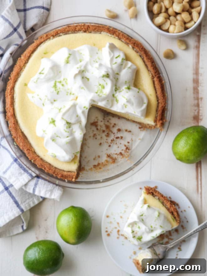 Close-up of a Tequila Key Lime Pie slice, showing the creamy filling, macadamia nut crust, and fresh lime garnish.