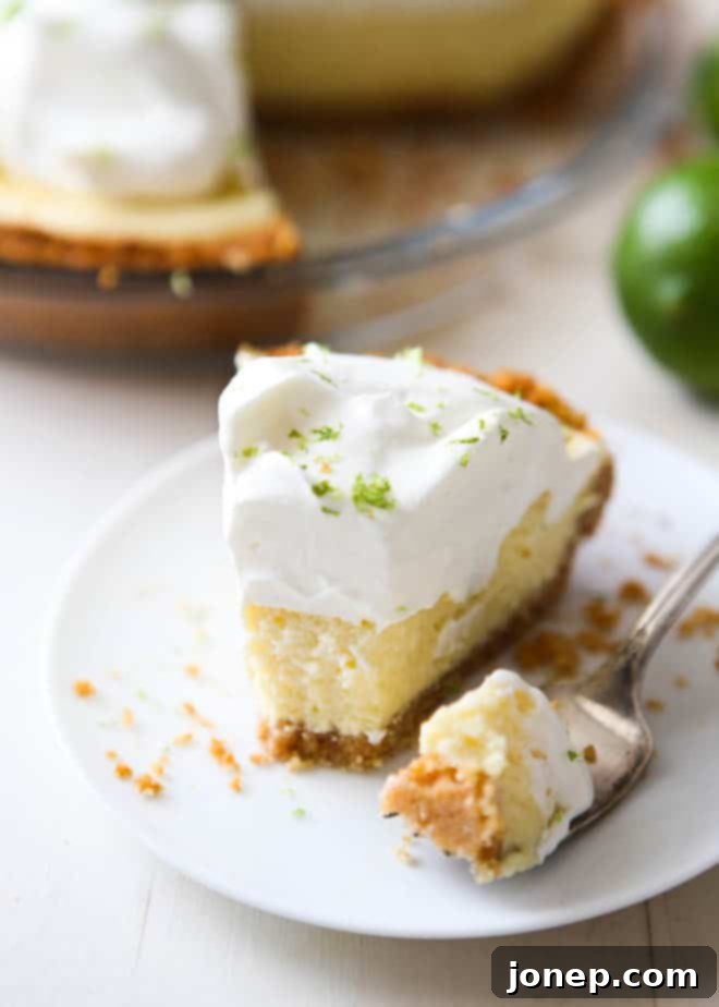 A whole Tequila Key Lime Pie topped with whipped cream and fresh lime slices, ready to be served.