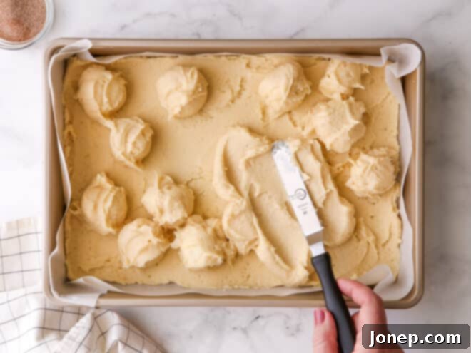 spreading gooey butter layer over cookie base with spatula