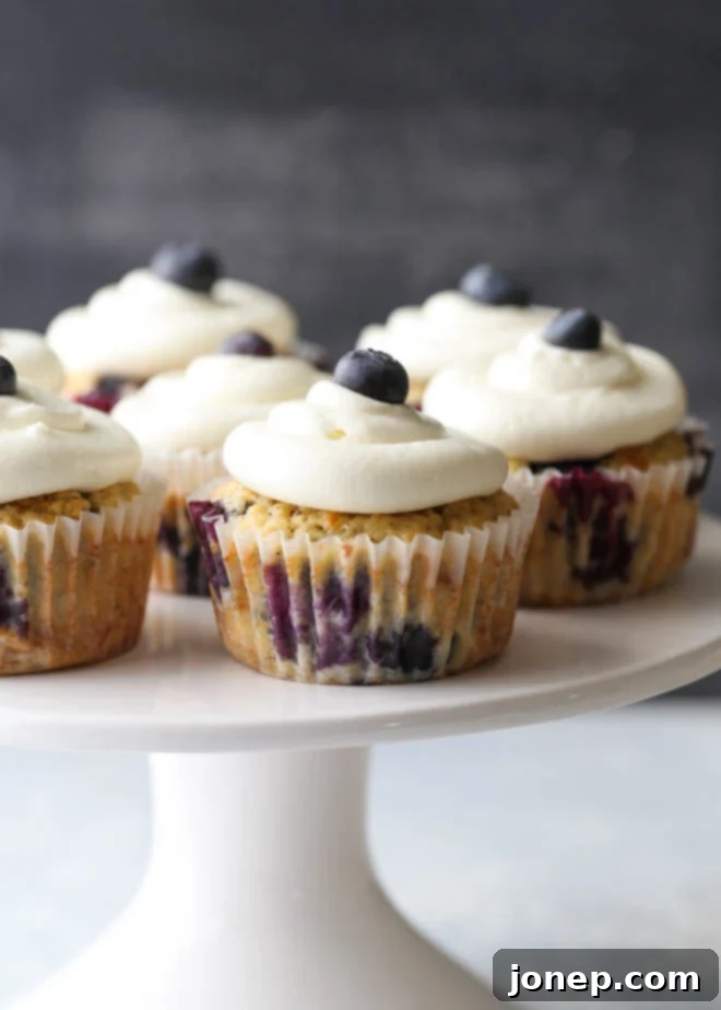 Blueberry muffin cupcakes with lemon cream cheese frosting, beautifully arranged on a white serving tray for a party.