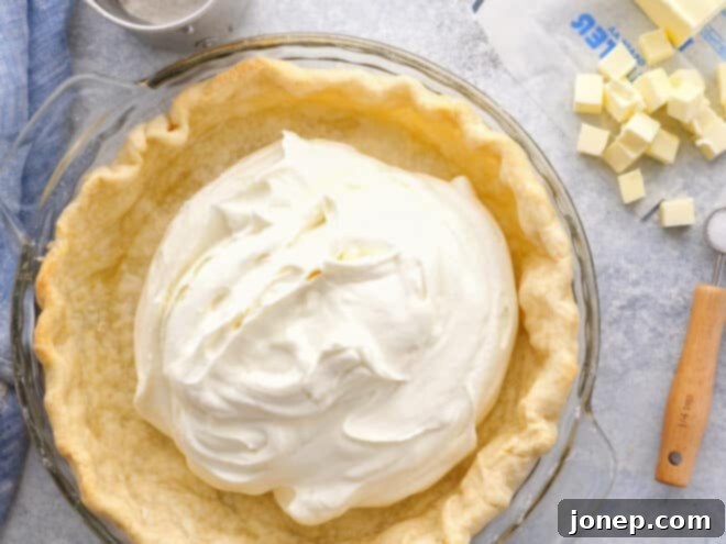 Master Blind Baking for Flawless Pie Crusts 3 Fully blind baked pie crust being carefully filled with a smooth, light-colored cream filling.