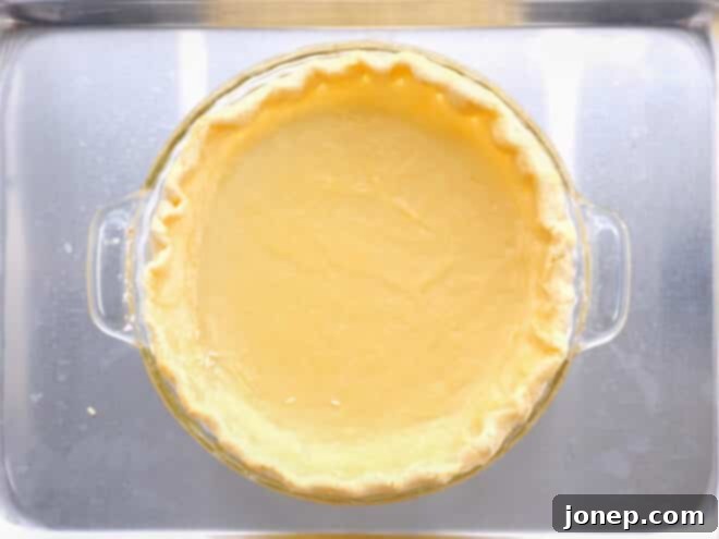 Master Blind Baking for Flawless Pie Crusts 7 Partially baked pie crust after removing weights, showing a light golden color on the edges and a still pale center, ready for filling.