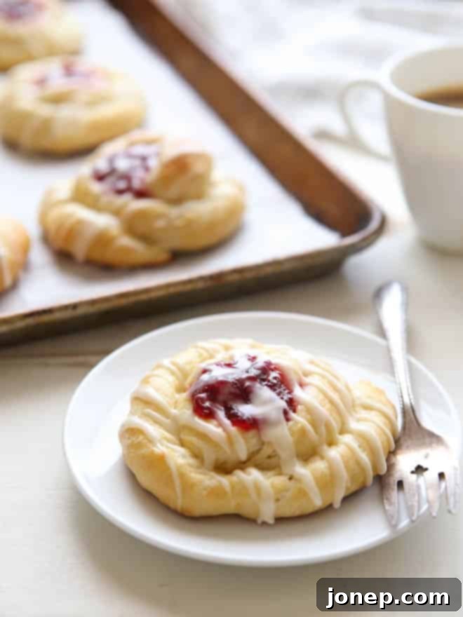 Spiced Cranberry Orange Danishes with a flaky, golden crust and vibrant cranberry filling, garnished with orange glaze. | completelydelicious.com