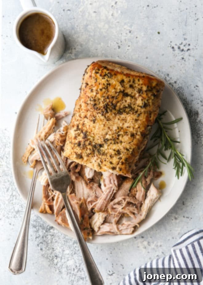 slow cooker rosemary balsamic pork roast shredded on a plate with gravy on the side
