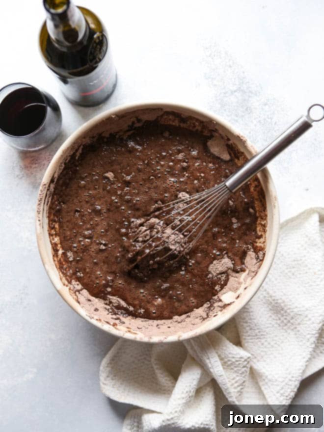 Slice of Red Wine Chocolate Cake with raspberry frosting revealing moist layers and rich chocolate