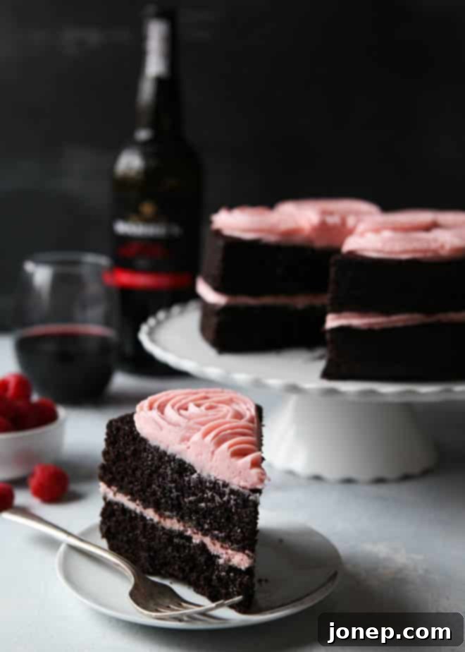 Finished Red Wine Chocolate Cake decorated with fresh raspberries and a light dusting of powdered sugar on a cake stand