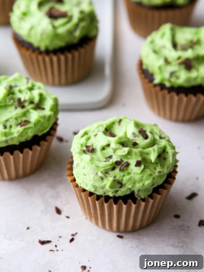 Minty Cocoa Bliss Cupcakes 9 A stack of perfectly baked and frosted mint chocolate chip cupcakes, artfully arranged on a white cake stand, ready for serving or gifting.