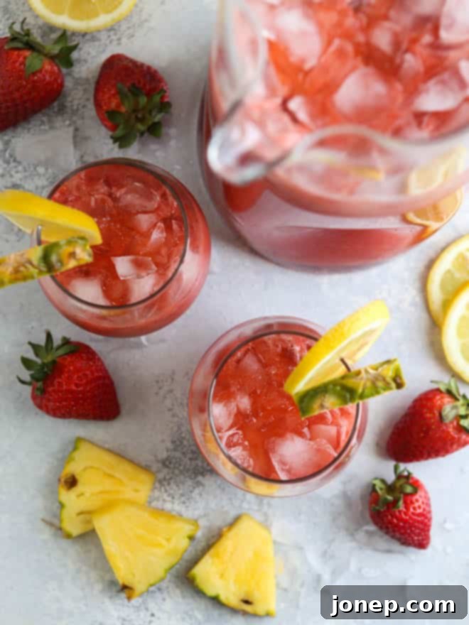 Serving Strawberry Pineapple Punch in individual glasses with fresh strawberry and lemon slices
