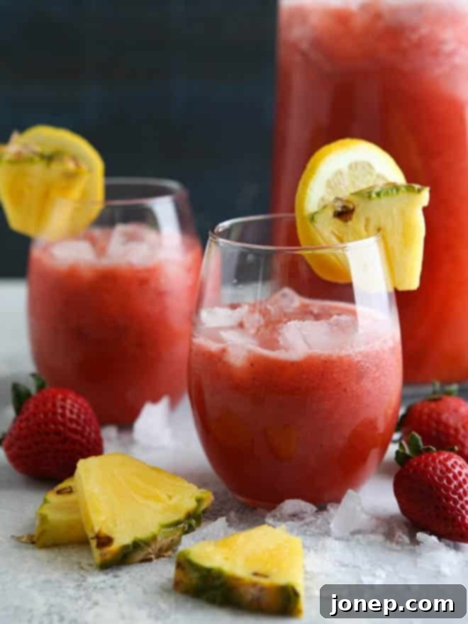 Overhead shot of Strawberry Pineapple Punch in a large glass pitcher with floating fruit