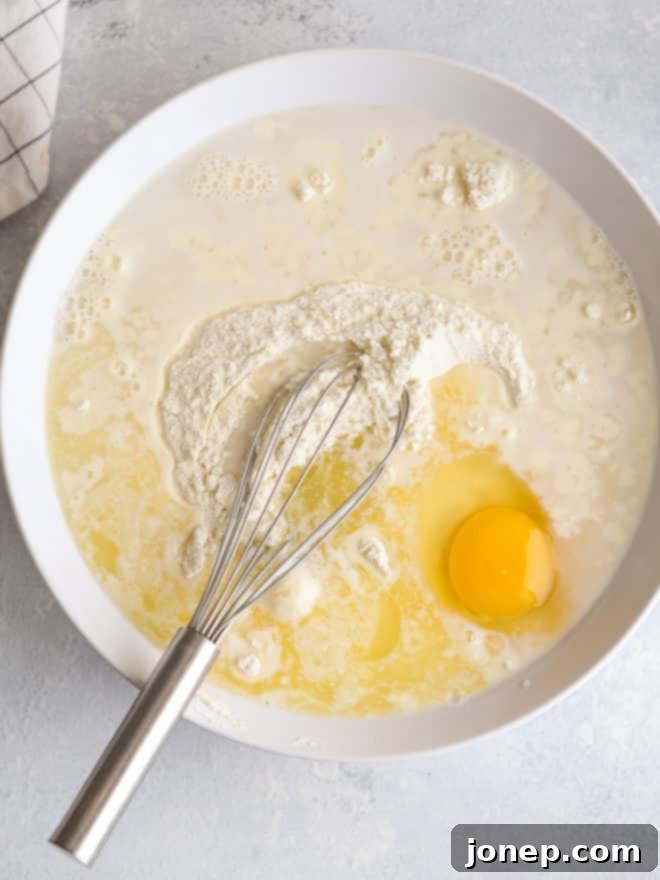 mixing pancake batter with homemade buttermilk pancake mix, egg, and water in a bowl with a whisk