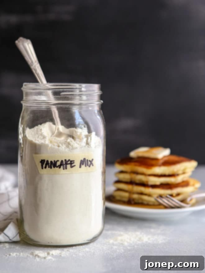 homemade buttermilk pancake mix in a jar with a stack of fluffy pancakes on a plate in the background
