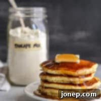 stack of pancakes on a plate with jar of buttermilk pancake mix in background