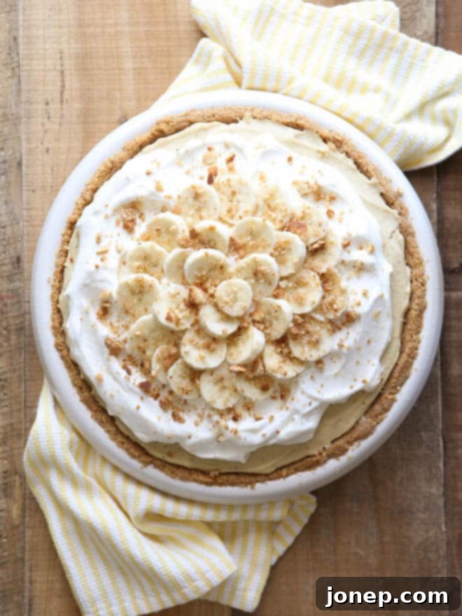 Decadent slice of Bourbon Banana Cream Pie with a thick whipped cream topping and a hint of vanilla wafer crust visible.