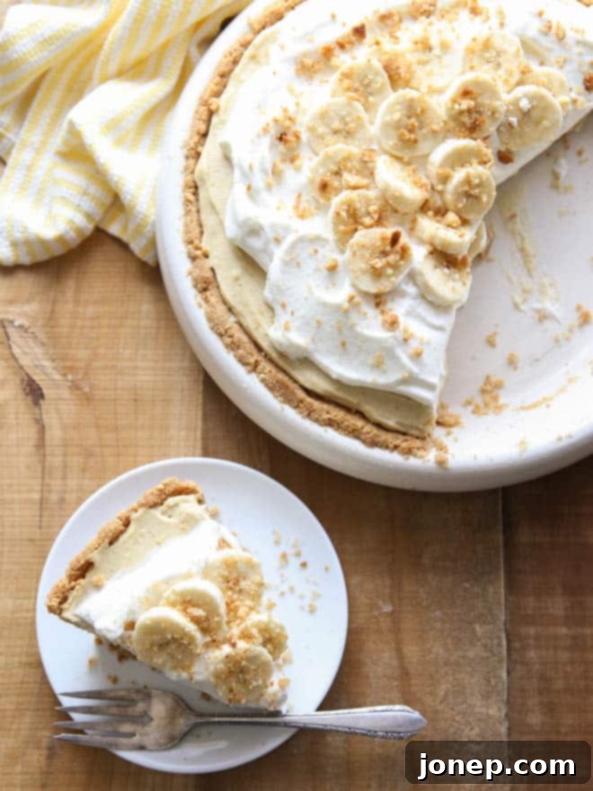 Top-down view of a complete Bourbon Banana Cream Pie, generously topped with whipped cream and garnished with fresh banana slices.
