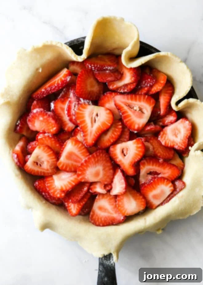 Rustic Strawberry Skillet Pie 5 sliced strawberries in pie crust inside skillet