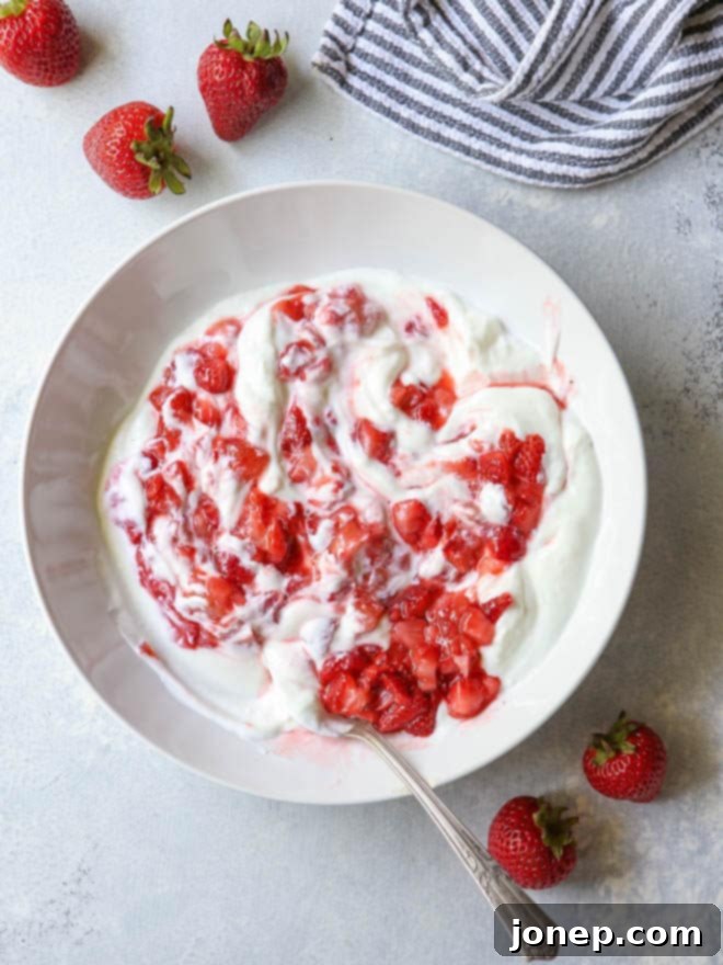 Roasted strawberries swirled with creamy yogurt, creating a vibrant and enticing mixture for popsicles.