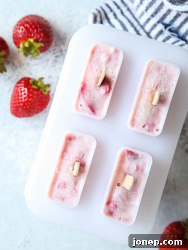 Popsicle molds filled with roasted strawberry yogurt mixture, ready to be placed in the freezer.