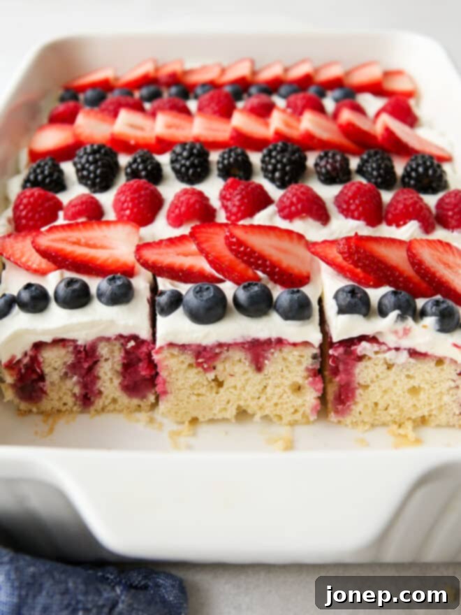 Berry Infusion Cake 3 Close-up of the homemade berry poke cake with a beautiful berry topping and fluffy whipped cream