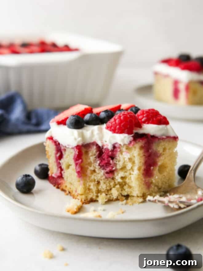 Berry Infusion Cake 10 Close up of a vibrant homemade berry poke cake, showing a generous layer of whipped cream and fresh berries