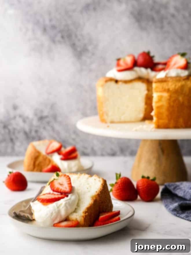 Sliced angel food cake served on plates with whipped cream and fresh strawberries
