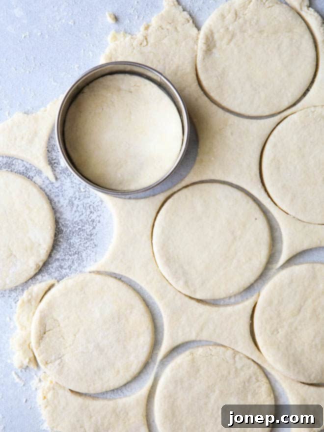Close-up of rolling out homemade buttermilk biscuit dough on a lightly floured surface