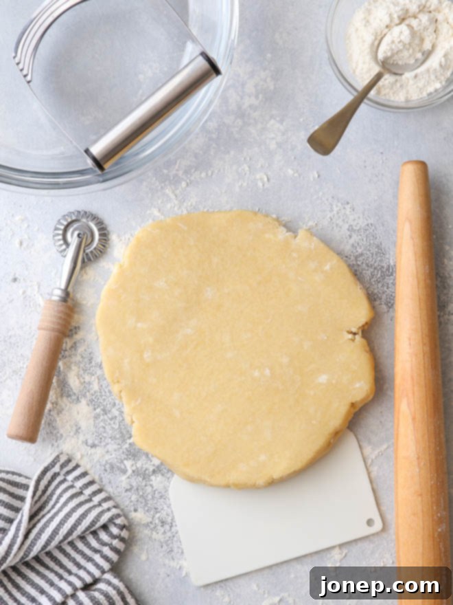 A collection of essential pie baking tools, including a rolling pin, pastry blender, pie dish, and more, laid out on a clean surface.