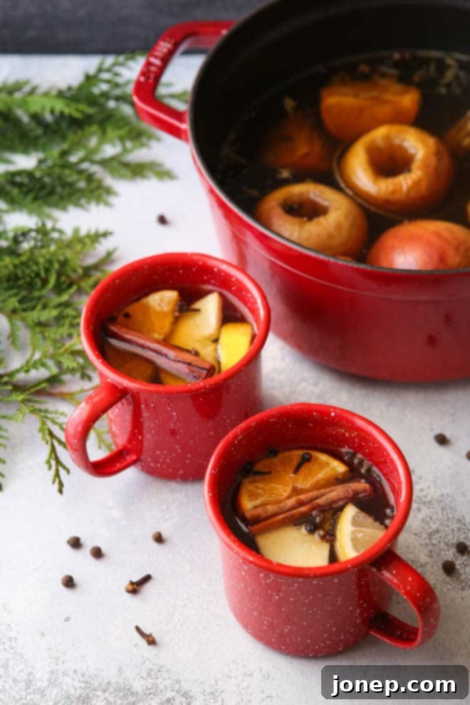 A mug of boozy hot wassail garnished with an orange slice and cinnamon stick, on a rustic wooden surface, exuding holiday cheer.