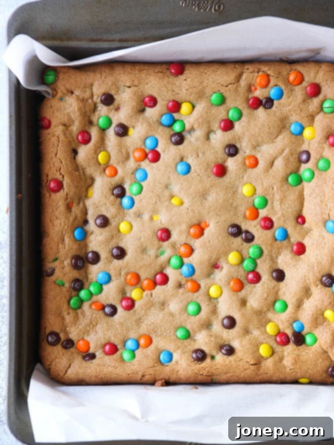 Stack of freshly sliced Peanut Butter M&M Cookie Bars on a cooling rack