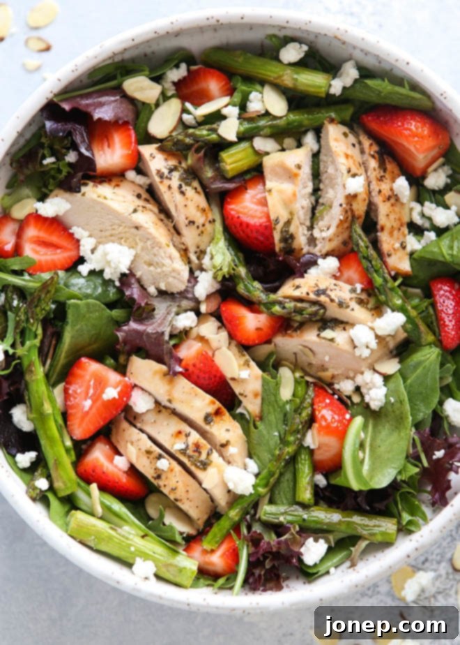 Freshly prepared strawberry asparagus salad with roasted chicken and vibrant greens