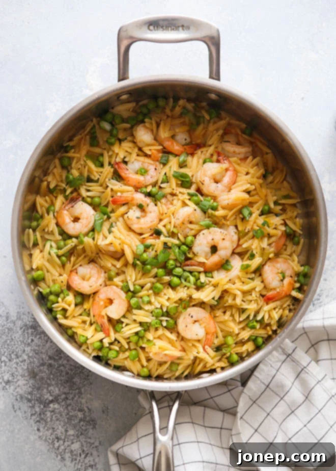 Delicious one-pot shrimp and pea orzo served in a bowl, ready to eat, garnished with fresh herbs.