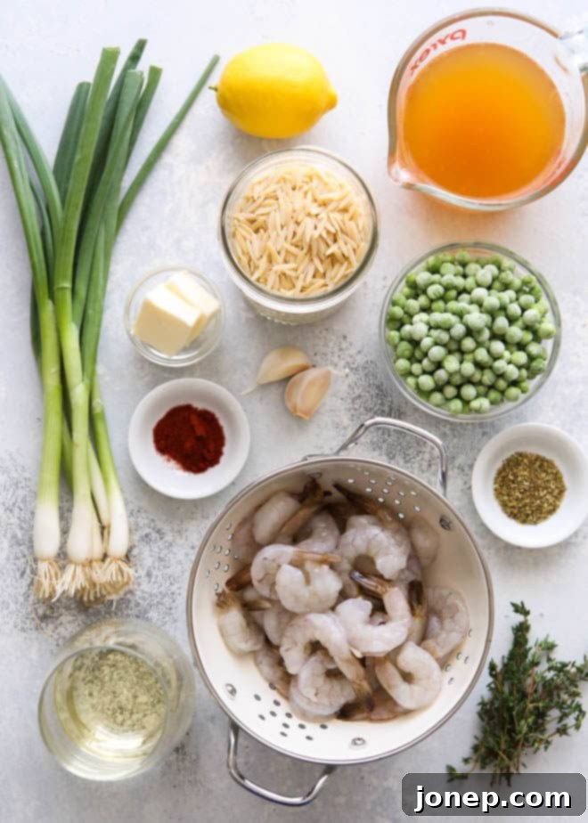 Fresh ingredients laid out for preparing one-pot shrimp and pea orzo, including uncooked orzo, raw shrimp, fresh garlic, lemon, and a bundle of green onions.