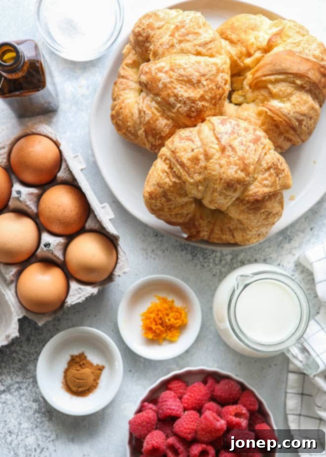 Ingredients for the best croissant French toast laid out, including croissants, eggs, milk, sugar, vanilla, cinnamon, and orange zest